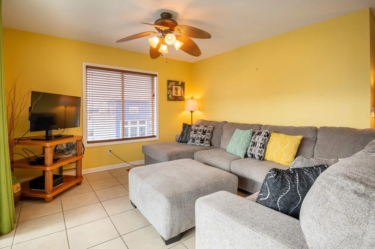 A cozy living room with a sofa, television, window, and lamp, arranged for relaxation or social gatherings. The window offers a hint of natural light, suggesting a connection to the outside environment and views beyond.