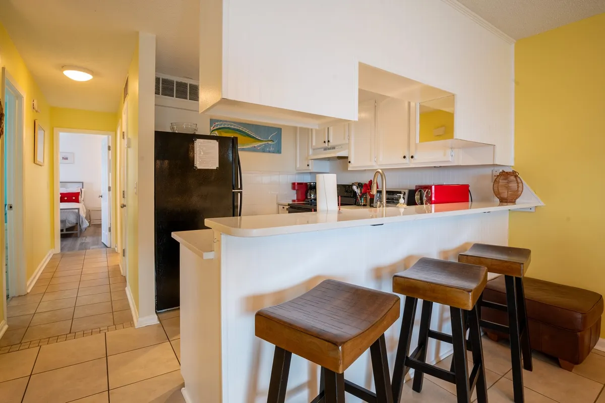 A stylish, modern kitchen featuring a large island with bar stools, sleek quartz countertops, stainless steel kitchen appliances, and tasteful wall art. The open design invites both meal preparation and socializing, with ample workspace and comfortable seating.